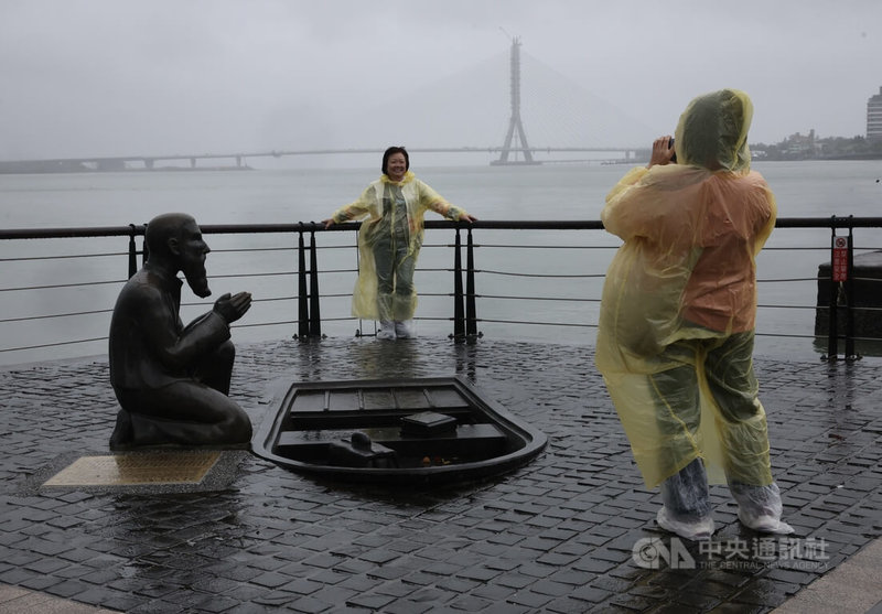 颱風鳳凰逼近台灣，氣象署表示，鳳凰最接近台灣的時間點是12日到13日，預估12日傍晚到晚間左右會登陸高屏一帶，13日清晨從台東出海。圖為新北淡水老街，觀光客穿著雨衣冒雨拍照留念。中央社記者趙世勳攝　114年11月11日