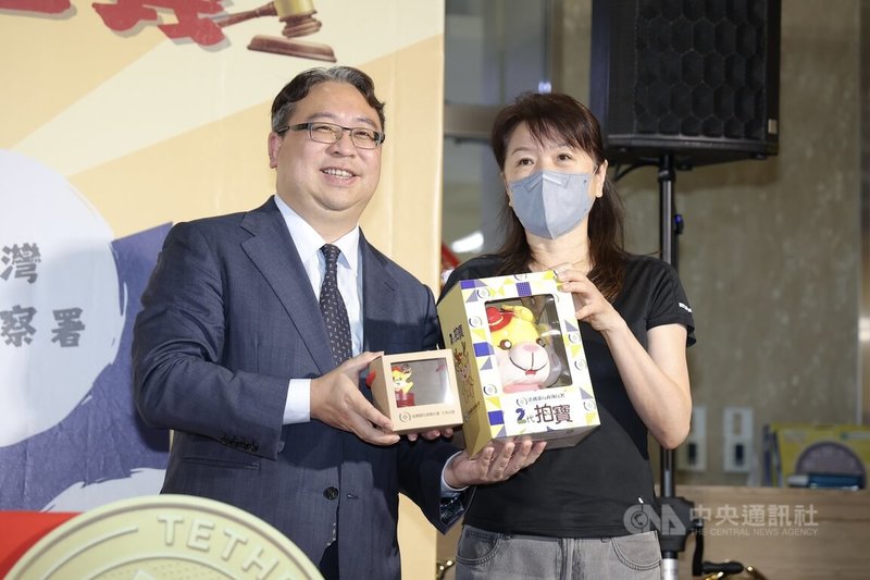 法務部行政執行署11日上午舉辦「檢執聯防 守護正義」拍賣活動，因應雙11購物節，法務部政務次長黃世杰（左）贈禮給首位得標泰達幣的民眾。中央社記者翁睿坤攝　114年11月11日