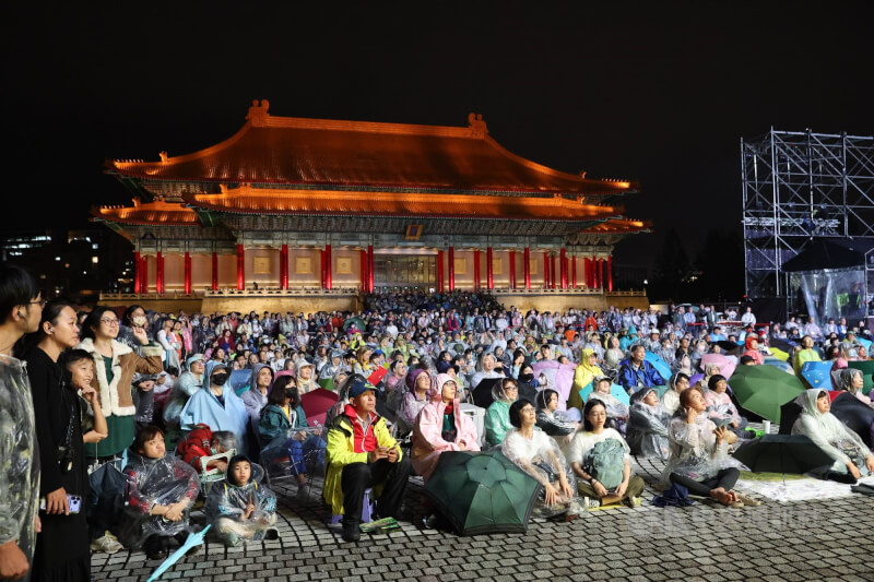 柏林愛樂訪台，在台北國家音樂廳帶來3場音樂會，13日晚間場次，兩廳院藝文廣場戶外同步轉播，民眾穿著雨衣在廣場席地而坐觀賞。中央社記者吳家昇攝　114年11月13日