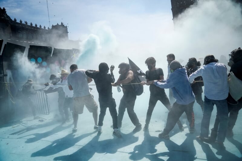 墨西哥市15日有數千人走上市區街頭抗議政府的治安政策，圖為示威者試圖拉倒路障。（路透社）