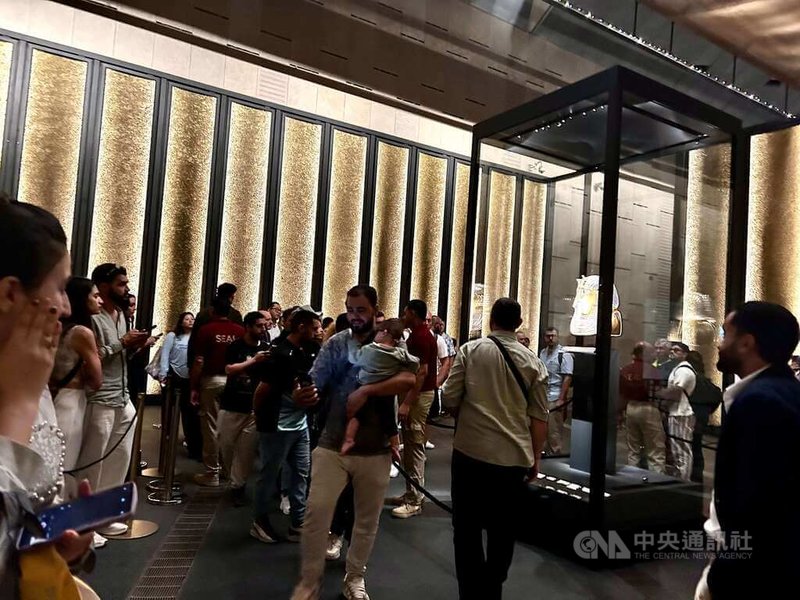 閃閃發亮的黃金面具以10公斤純黃金為底打造，並鑲嵌青金石和琉璃等瑰麗寶石，是大埃及博物館展廳最大館藏亮點，展示櫃前人潮不斷。遊客紛紛舉起手機或相機，拍照與這場輝煌歷史共同留念。中央社記者施婉清開羅攝　114年11月18日