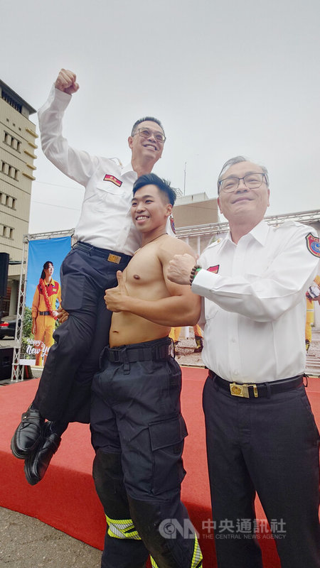 嘉義縣消防局猛男桌曆18日發表,桌曆猛男主角之一的消防局鹿草分隊隊員官昱辰(中),展現強壯體魄,直接扛起消防局長蔡建安(左)。中央社記者蔡智明攝 114年11月18日