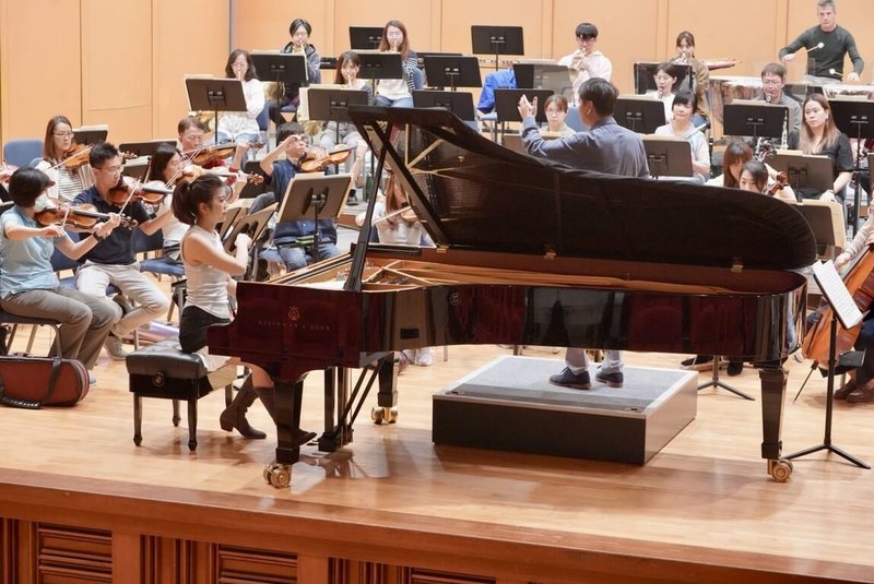 國立台灣交響樂團首席客席指揮水藍（前右背對立者）與鋼琴家陳毓襄（前左）2度合作，將於台中、高雄帶來國台交80週年團慶音樂會。圖為樂團排練情形。（國台交提供）  中央社記者趙靜瑜傳真　114年11月19日