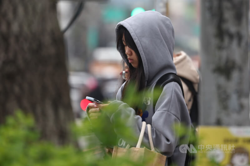 圖為新北市土城區外出民眾穿起連帽上衣禦寒。（中央社檔案照片）