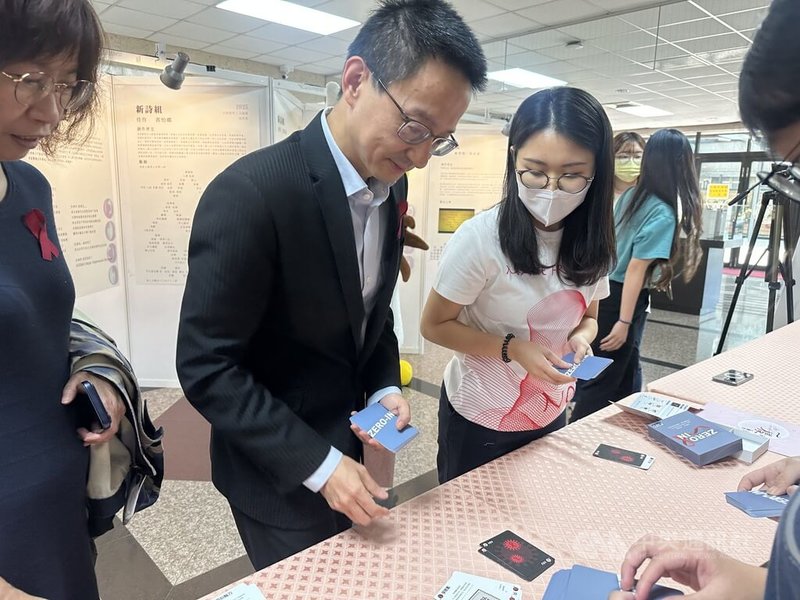 中山醫學大學25日舉辦「圖書館週暨世界愛滋病日系列活動」開幕式,衛生福利部疾病管制署長羅一鈞體驗桌遊,透過遊戲傳遞公共衛生知識。中央社記者趙麗妍攝 114年11月25日