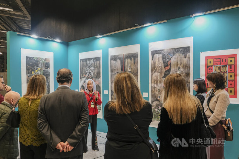 台灣作為主賓國參加西班牙第14屆畢爾包藝術博覽會(FIG Bilbao),由水墨畫家黃淑卿(後排右)深具台灣文化特色的「夜八鸝」等4幅大型創作,與「台灣現代版畫之父」廖修平充滿傳統節慶喜悅的「符號系列」,共同占據展會入口處黃金展位,圖為策展人周芳蓮(紅衣)為觀展貴賓進行導覽。中央社記者胡家綺馬德里攝 114年11月29日