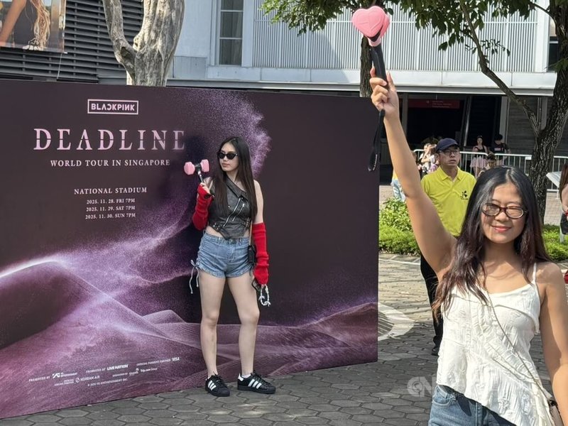 韓國女團BLACKPINK 11月28日至30日在新加坡巡演。圖為粉絲29日在新加坡國家體育場外與活動背板拍照。中央社記者吳昇鴻新加坡攝　114年12月1日