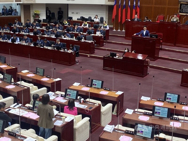 民進黨台北市議員簡舒培（前背對立者）1日質疑，民眾黨新住民委員會主委徐春鶯涉反滲透法遭羈押，北市府卻曾聘其為新住民委員會委員；市長蔣萬安（後右藍西裝者）表示，是社團推薦，會請民政局依相關規定進行追究、調查。中央社記者黃麗芸攝　114年12月1日