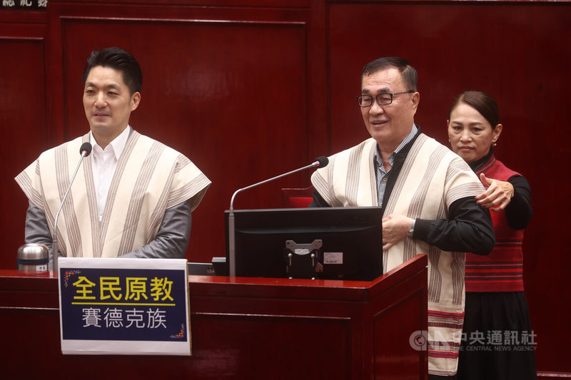 台北市議會2日繼續進行市政總質詢，國民黨籍議員李傅中武質詢時特別送上賽德克族的戰袍背心給副市長李四川（前右），還強調要贏得新北市長選舉「非你莫屬」，呼籲李四川勇於承擔。李四川則稱今天在台北市、不談新北市。左為台北市長蔣萬安。中央社記者王騰毅攝  114年12月2日