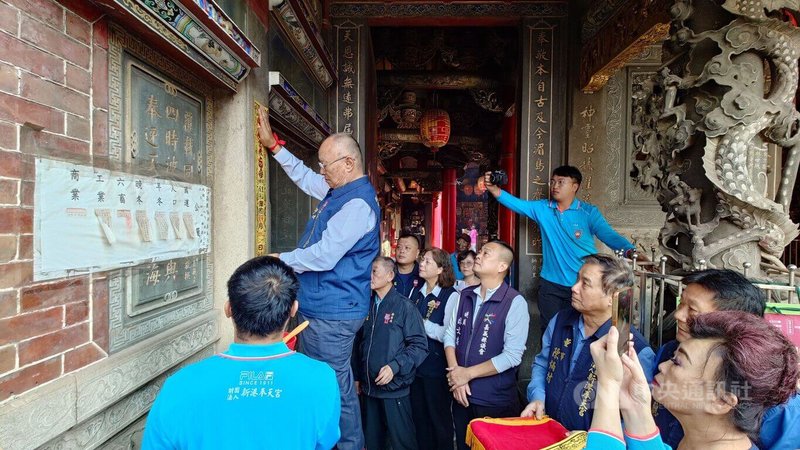 新港奉天宮董事長何達煌（登高者）2日在奉天宮入口兩側貼上香條，為「阿里山神旅行」活動揭開序幕。中央社記者蔡智明攝　114年12月2日