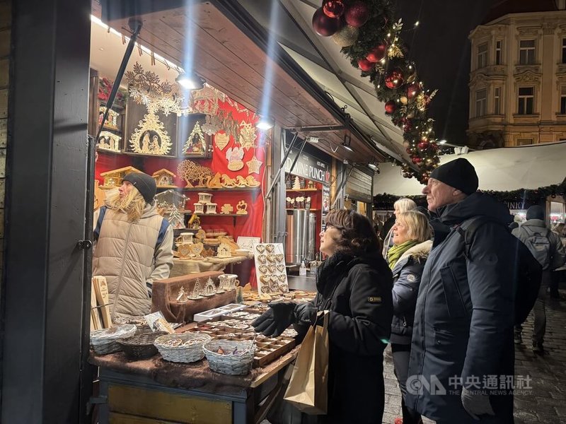 布拉格舊城廣場的耶誕市集有許多傳統美食攤位，如煙囪捲、香腸、熱紅酒，遊客可購買主題紡織品、木製玩偶或吹製玻璃球飾，現場還有音樂表演。中央社記者劉郁葶布拉格攝 114年12月5日