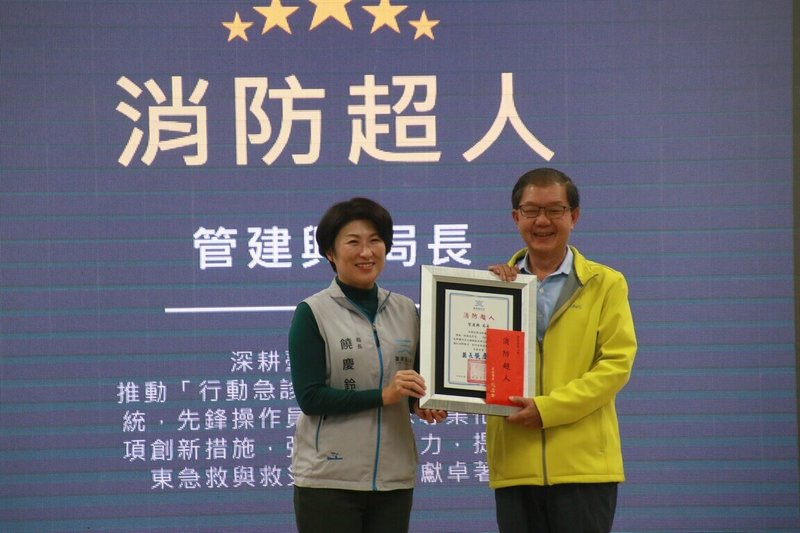 擔任台東縣消防局長27年、在消防服務逾40年的管建興（右），即將在115年1月退休，台東縣長饒慶鈴（左）4日頒贈「消防超人」獎牌，感謝他始終堅守救災第一線。（台東縣政府提供）中央社記者盧太城台東傳真　114年12月5日