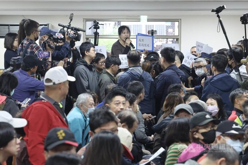 社子島自救會9日社子島區段徵收公聽會指北市府違法程序，社子島自救會發言人李華萍（後中，棕衣立者）拿起麥克風喊話要求停止區段徵收，並尊重在地居民意願。中央社記者趙世勳攝 114年12月9日