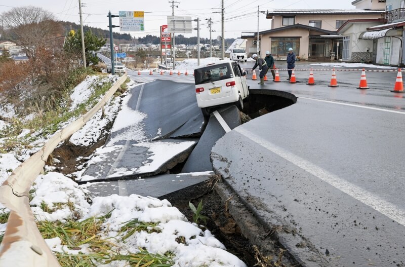 日本青森縣外海8日深夜發生強烈地震出現道路崩塌災情，9日現場管制交通。（共同社）