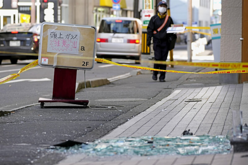 日本青森縣8日發生震度6強地震，圖為青森縣八戶市道路出現碎裂的玻璃，周圍拉起封鎖線並有警語提醒路人注意。（共同社）
