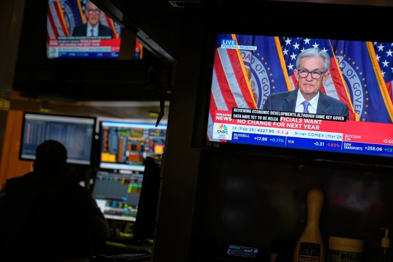 美國聯準會10日宣布降息一碼，紐約證券交易所大廳內螢幕播放聯準會主席鮑爾記者會畫面。（美聯社）