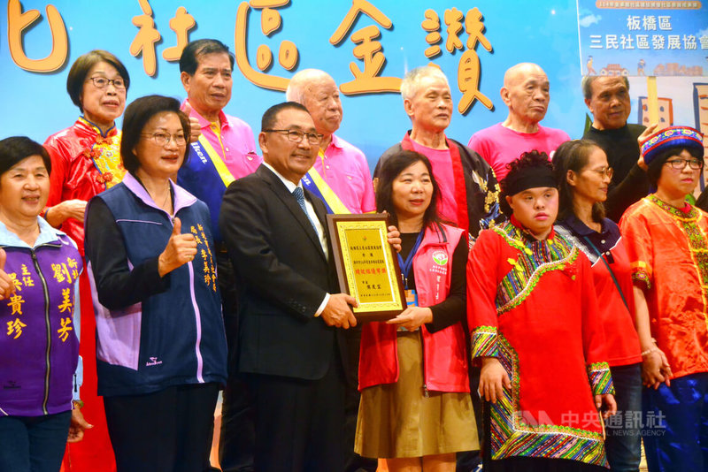 新北市政府12日舉行「114年度金卓越社區選拔績優社區表揚暨成果展」，市長侯友宜（前左3）會中頒獎表揚獲績效組優等獎的板橋區三民社區發展協會。中央社記者黃旭昇新北市攝　114年12月12日