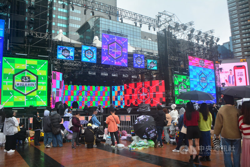 新北市板橋區12日午後飄小雨、氣溫下滑，但在歡樂耶誕城將登場的演唱會舞台前，仍有大批熱情粉絲冒雨聚集關注彩排狀況，卡位爭睹偶像風采。中央社記者黃旭昇新北市攝　114年12月12日