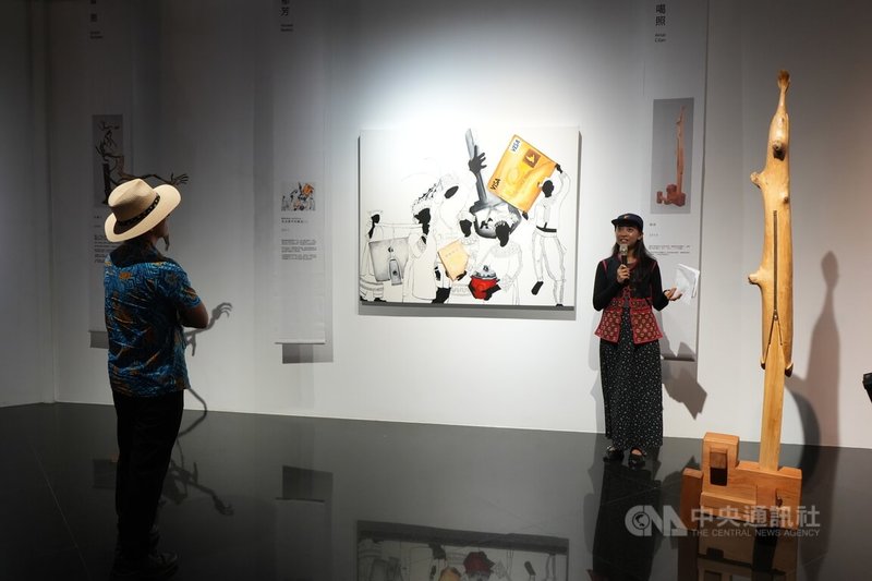 「原典–台灣原住民族當代藝術品典藏特展」12日起在屏東登場，原發中心藝術展演組策展人連曦（右）現場導覽解說藝術家馬郁芳畫作，畫面呈現排灣族婚禮抬聘禮，卻以信用卡、3C產品等現代元素取代傳統物件，讓人省思現代族人如何重新定義自己。中央社記者黃郁菁攝　114年12月12日