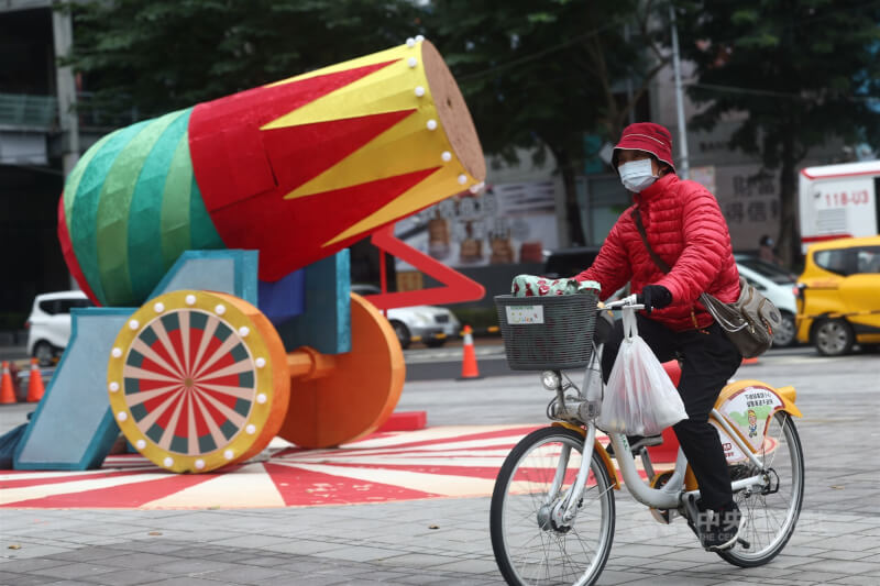 中央氣象署表示，13日晚間起大陸冷氣團南下，14日至15日清晨台南以北、宜蘭及花蓮低溫約12到15度。圖為新北市板橋區歡樂耶誕城周邊，單車騎士穿著羽絨外套保暖。中央社記者王騰毅攝 114年12月12日