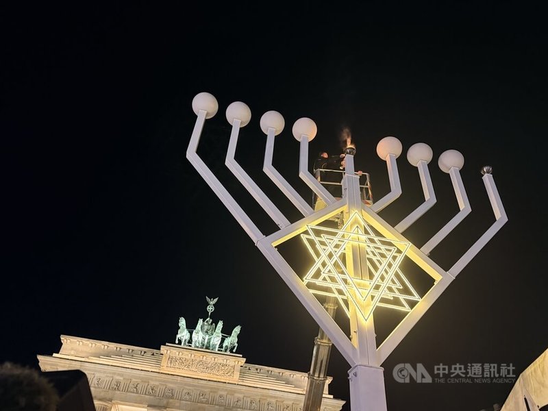 柏林猶太社群14日晚間在布蘭登堡門前舉行光明節點燈儀式，雲梯車升至高空，由猶太拉比點燃高約10公尺的光明節燭台第一道燭光。中央社記者林尚縈柏林攝　114年12月15日
