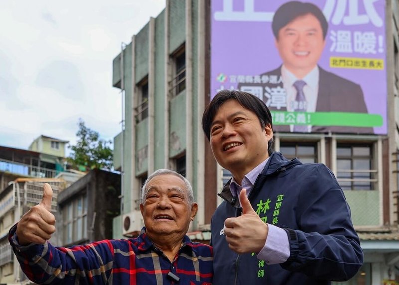 民進黨宜蘭縣長提名人林國漳（右）15日在自己出生、成長地宜蘭市北門口懸掛首面競選看板，並與兒時租屋處房東蔡清滿（左）合影留念。（林國漳提供）中央社記者王朝鈺傳真　114年12月15日