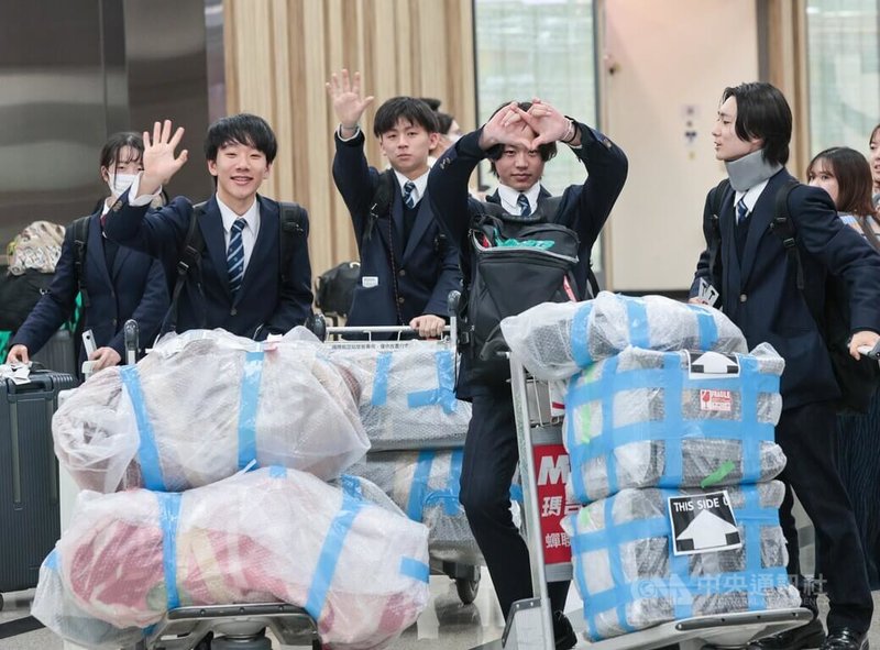 擁有「翡翠騎士」之稱的日本東京農業大學第二高等學校吹奏樂部17日晚間抵達台北松山機場，看見媒體熱情比出愛心手勢。中央社記者王寶兒攝　114年12月17日