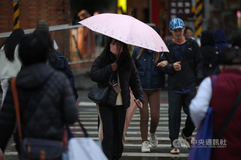 氣象署17日指出，18日受東北季風影響，北北基宜要留意局部較大雨勢。。圖為新北市汐止區民眾午後穿著羽絨衣撐傘擋雨。（中央社檔案照片）