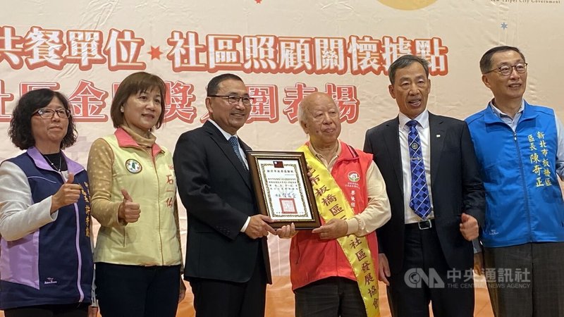 新北市政府19日表揚114年績優老人共餐單位，市長侯友宜（左3）會中頒發獎狀給板橋區三民社區發展協會，由餐飲組長謝阿毛（右3）代表受獎。中央社記者黃旭昇新北市攝　114年12月19日