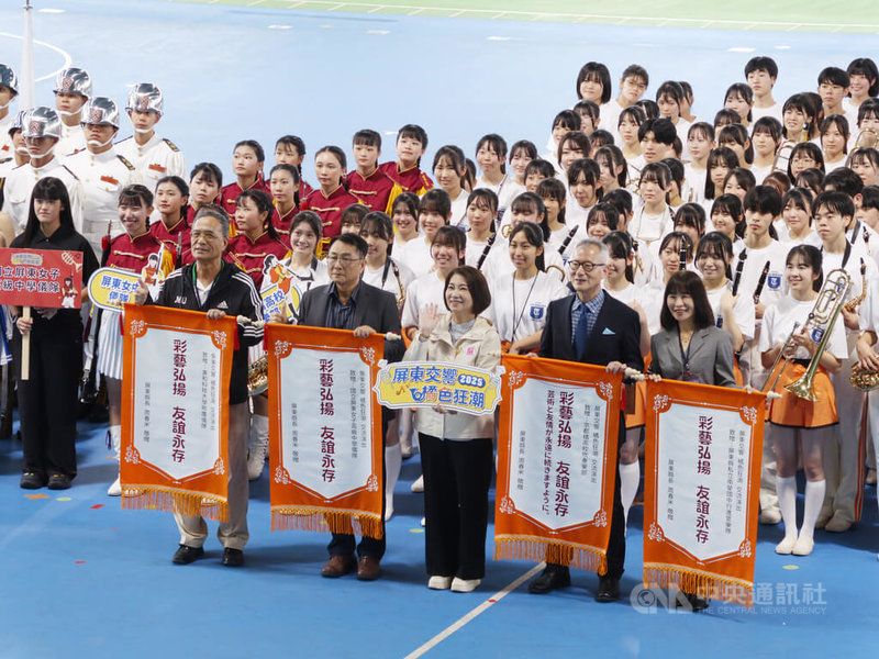 有「橘色惡魔」之稱的京都橘高校吹奏樂部20日首度前進屏東演出,與在地3校同台交流,屏東縣長周春米(前中)也到場共襄盛舉,並頒發錦旗給4校樂儀隊。中央社記者黃郁菁攝 114年12月20日