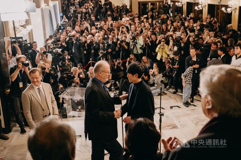 美國華裔鋼琴家陸逸軒（Eric Lu）（中右）日前在第19屆蕭邦國際鋼琴大賽榮獲金獎，評審團主席、美國鋼琴家歐爾森（Garrick Ohlsson）（中左）宣布名次時，與陸逸軒握手致意。（International Fryderyk Chopin Piano Competition提供，攝影Wojciech Grzedzinski）  中央社記者趙靜瑜傳真　114年12月22日