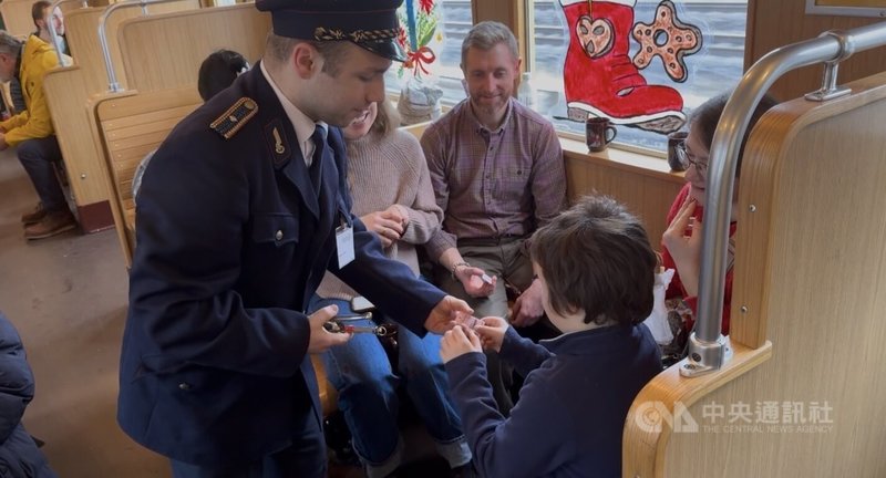 柏林懷舊耶誕列車車廂內,身穿東德時期鐵路制服的「柏林城市歷史快鐵協會」成員史蒂芬化身站務員,為小朋友的車票打孔,復刻票務系統尚未數位化的場景。中央社記者林尚縈柏林攝 114年12月23日