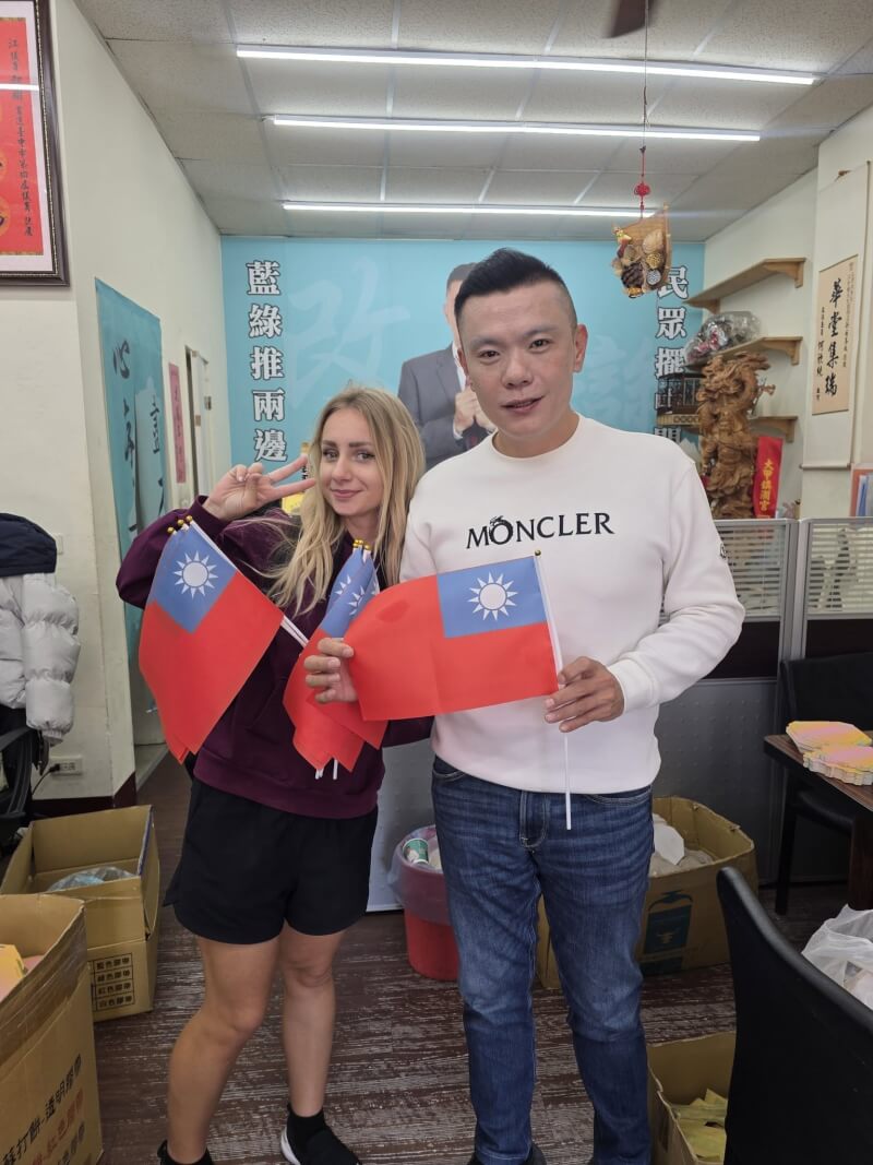 民眾黨台中市議員江和樹（右）遇外籍金髮女子自稱聾啞人士，以「籌措旅費」為由兜售國旗。（圖取自facebook.com/p/江和樹-100047297856752）