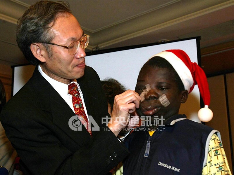 在非洲阿福的感恩歡送會上，長庚醫療團總召陳昱瑞（左），為他取下彈性頭套，並仔細揭下貼在臉部的膠帶。中央社記者吳繼昌攝　92年12月24日