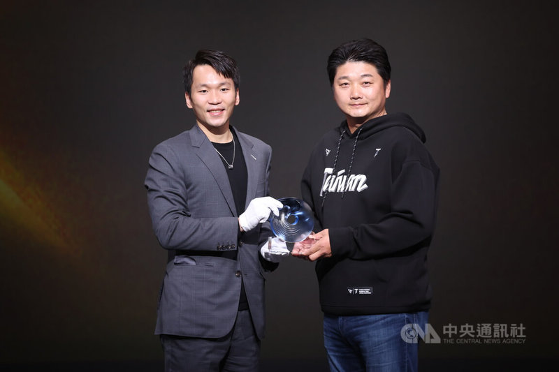 114年體育運動精英獎頒獎典禮24日在台北表演藝術中心登場，「最佳教練獎」由帶領台灣棒球代表隊拿下世界12強冠軍的曾豪駒（右）獲得，他從運動部長李洋（左）手中接過獎座。中央社記者張新偉攝　114年12月24日