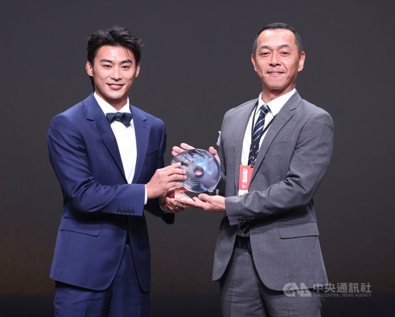 114年體育運動精英獎24日在台北頒獎，台灣拳擊好手黃筱雯獲選最佳女運動員，此項目已連2年由拳擊運動員獲獎。可惜黃筱雯因移地訓練無法親自出席，由叔叔（右）代表從柔道好手楊勇緯（左）手中接下獎座。中央社記者張新偉攝　114年12月24日