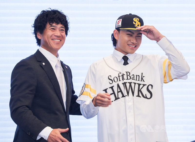 投手徐若熙（右）加盟日職福岡軟銀鷹隊，26日在台北舉行記者會，軟銀鷹隊首席棒球總管城島健司（左）送上軟銀球衣及球帽，徐若熙穿上後心情激動，露出笑容。中央社記者裴禛攝　114年12月26日