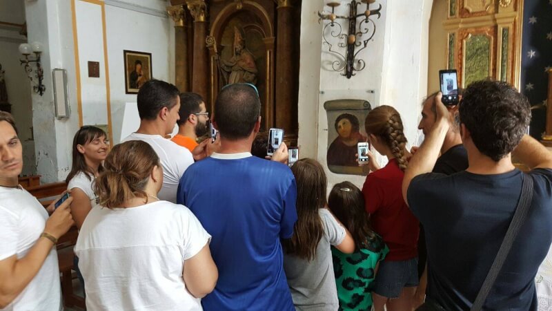 許多遊客造訪博哈小鎮觀賞修補後的耶穌畫像壁畫。(圖取自聖母慈悲教堂基金會facebook.com)