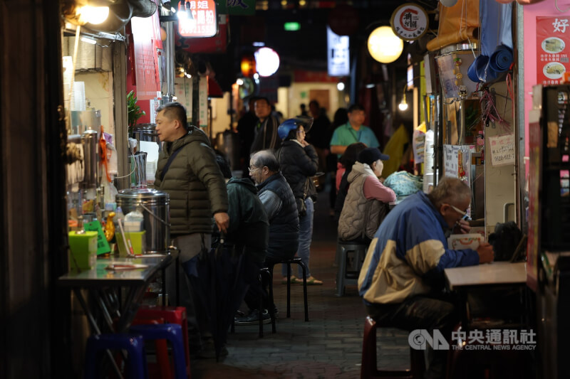 圖為新北市汐止區民眾穿著保暖衣物在外品嚐美食。（中央社檔案照片）