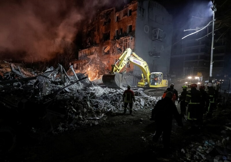烏克蘭東北部哈爾科夫州一棟公寓2日竄出濃煙，周圍散落著大塊建材，救援人員穿梭在瓦礫堆中救援。（路透社）