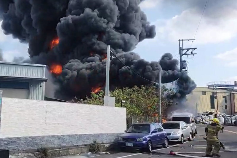 台南市永康區一處工廠附近，4日中午疑似有廢棄物燃燒，延燒至廠房及路旁停放車輛，竄出大量濃煙。（讀者提供）中央社記者楊思瑞傳真　115年1月4日