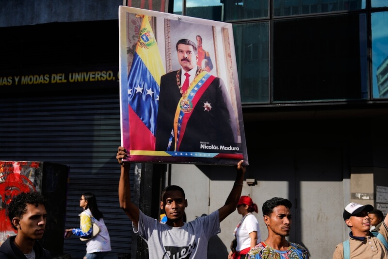 委內瑞拉首都卡拉卡斯民眾4日在街頭高舉總統馬杜洛的照片。（美聯社）