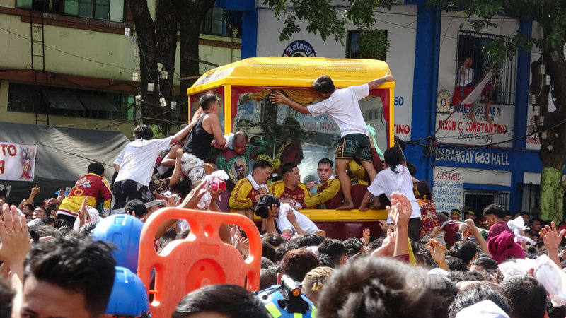 菲律賓天主教規模最大年度宗教盛事「黑拿撒勒人出巡」9日在馬尼拉市登場，民眾不顧危險攀爬神像座駕，用白毛巾擦拭玻璃框，獲得祝福。中央社記者林行健馬尼拉攝　115年1月9日