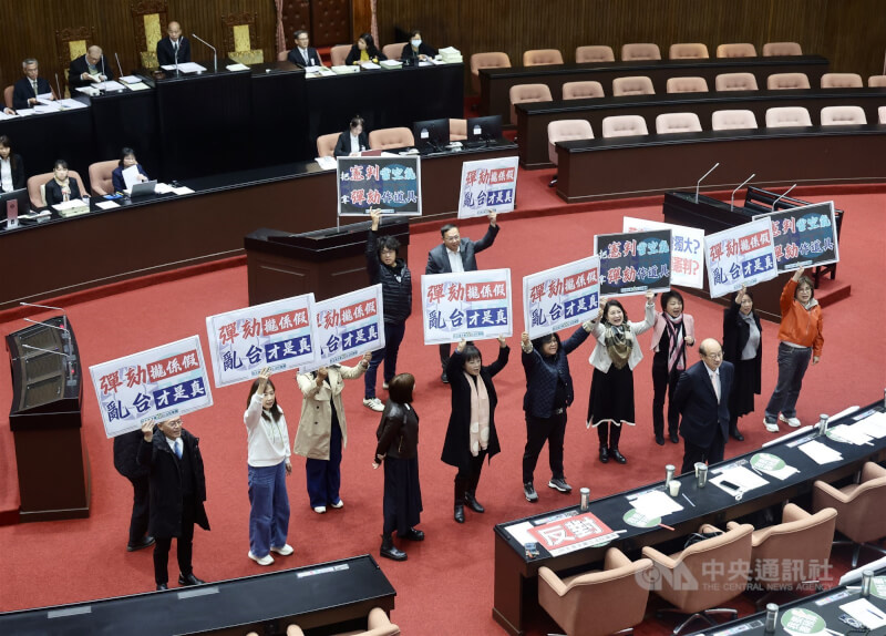 立法院會2025年12月26日開會，藍白挾人數優勢通過對總統賴清德啟動彈劾案程序，民進黨團在議場舉牌抗議。（中央社檔案照片）