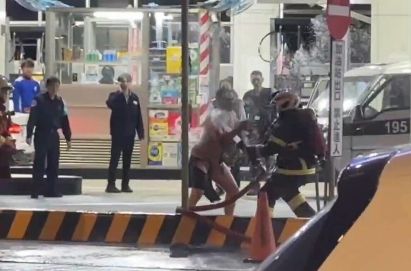 新北市板橋區民族路加油站9日晚間發生民眾點火,引發火警並波及正在加油的保全員事件。警方10日表示,犯嫌一度追打消防隊員,消防員已提出傷害與妨害公務罪告訴;圖為犯嫌攻擊消防人員。(徐姓民眾提供)中央社記者黃旭昇新北傳真 115年1月10日
