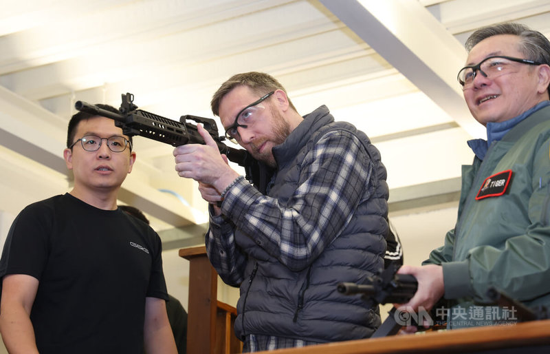 前美國陸軍上尉陶佛(中)、前美國國防部官員胡振東(右)赴彰化伸港怪怪貿易,試射T91擬真訓練BB槍。中央社記者張新偉攝 115年1月10日