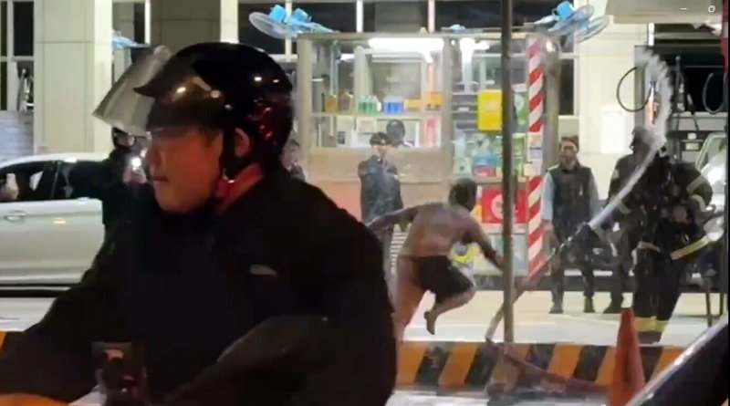 新北市板橋區民族路加油站9日晚間發生民眾點火,引發火警並波及正在加油的保全員事件。警方10日表示,犯嫌一度追打消防隊員,消防員已提出傷害與妨害公務罪告訴;圖為消防員以水柱處理時,犯嫌追打攻擊消防員。(徐姓民眾提供)中央社記者黃旭昇新北傳真 115年1月10日
