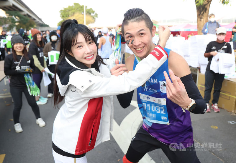 2026渣打台北公益馬拉松11日上午五點半在總統府前凱達格蘭大道起跑，中職樂天女孩在終點線為選手加油打氣，筠熹（左）為跑者掛上完賽獎牌。中央社記者張新偉攝 115年1月11日