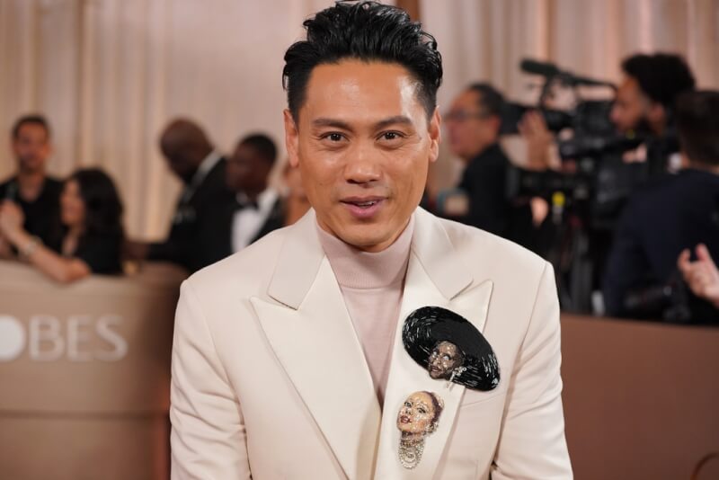 電影「魔法壞女巫：第二部」導演朱浩偉出席金球獎，他在西裝上別上兩位主演辛西婭艾利沃和亞莉安娜頭像的胸章。（美聯社）