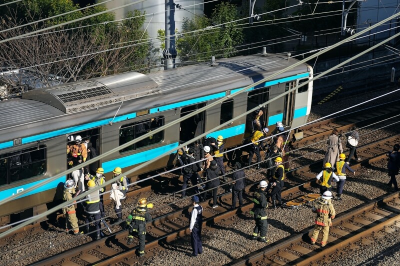 日本東京JR京濱東北線16日因停電停擺，工作人員在軌道上疏散旅客。（共同社）